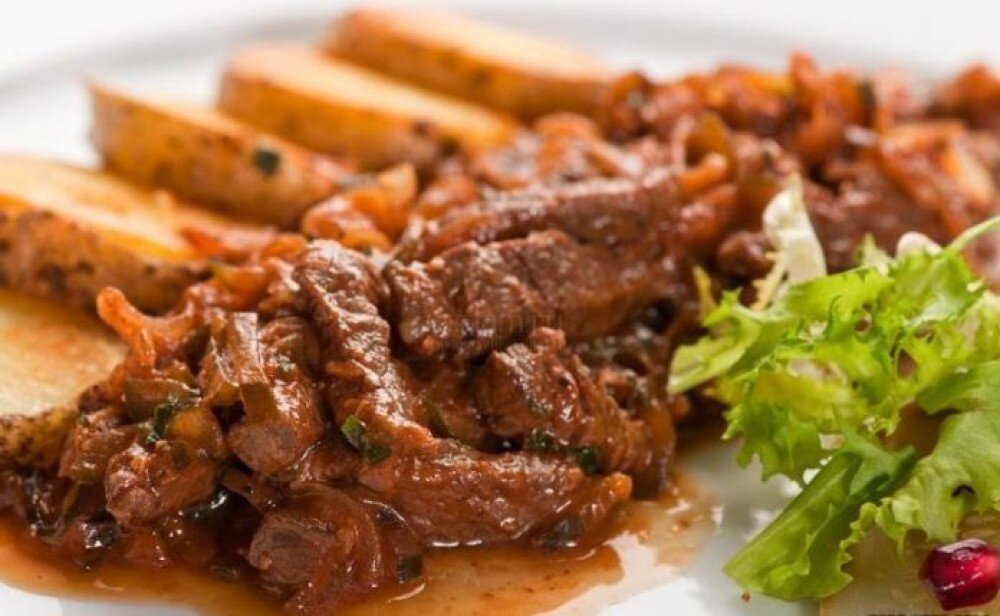 Гуляш из говядиной, тушенный с овощами и картофелем, подаётся с гарниром на выбор с доставкой